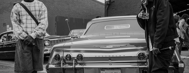 Black and white frame of a lowrider and onlookers at Open Hoist