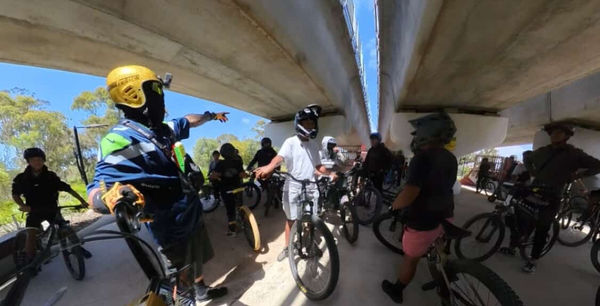 Group of riders rolling out under a freeway overpass