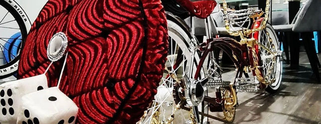 Red velvet upholstery and fuzzy dice detail on a show lowrider bicycle