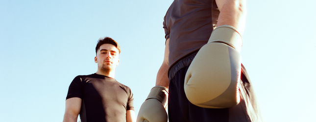 Boxer with gloves over his shoulder shot from below against the sky