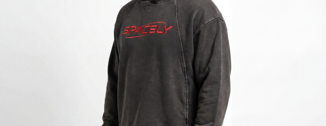 Brown Spacely crewneck with red chest logo on a plain backdrop