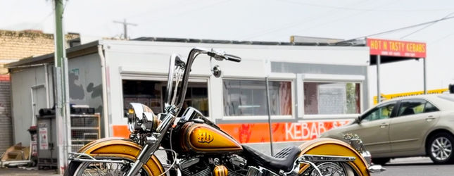 Yellow and chrome lowrider bicycle parked outside a suburban shopfront