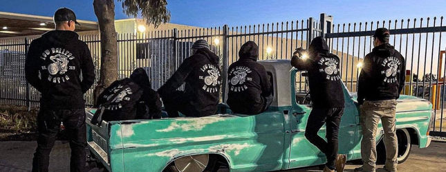 Low Ballers Mafia members in club jackets around a green classic car