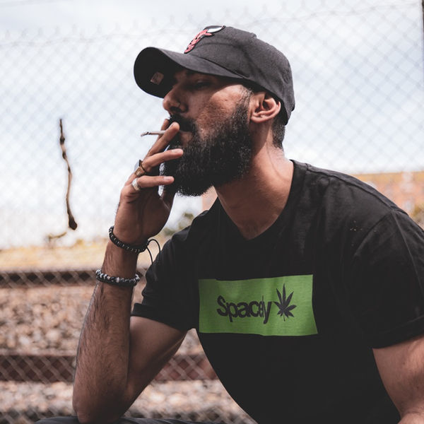 Man in a Spacely tee beside a wire fence