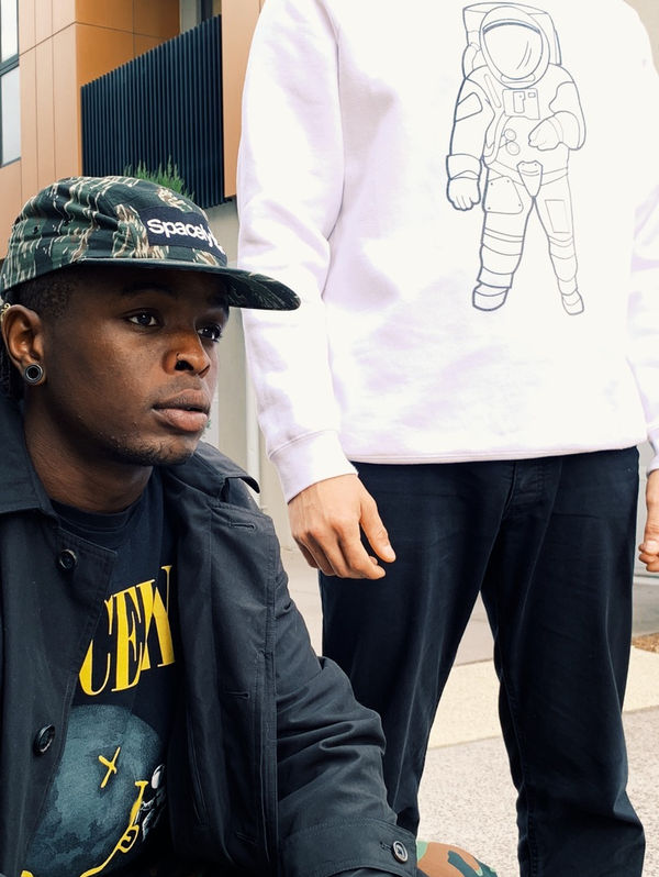 Man in a Spacely cap beside a white Spacely astronaut long-sleeve