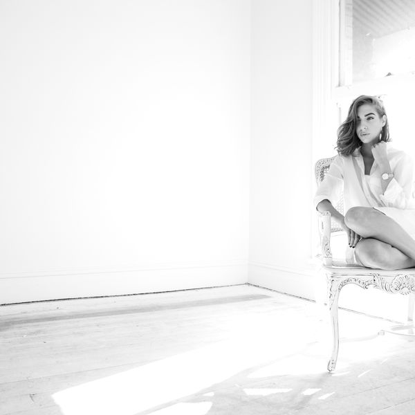 High-key black and white portrait of a woman on a chair in an empty room