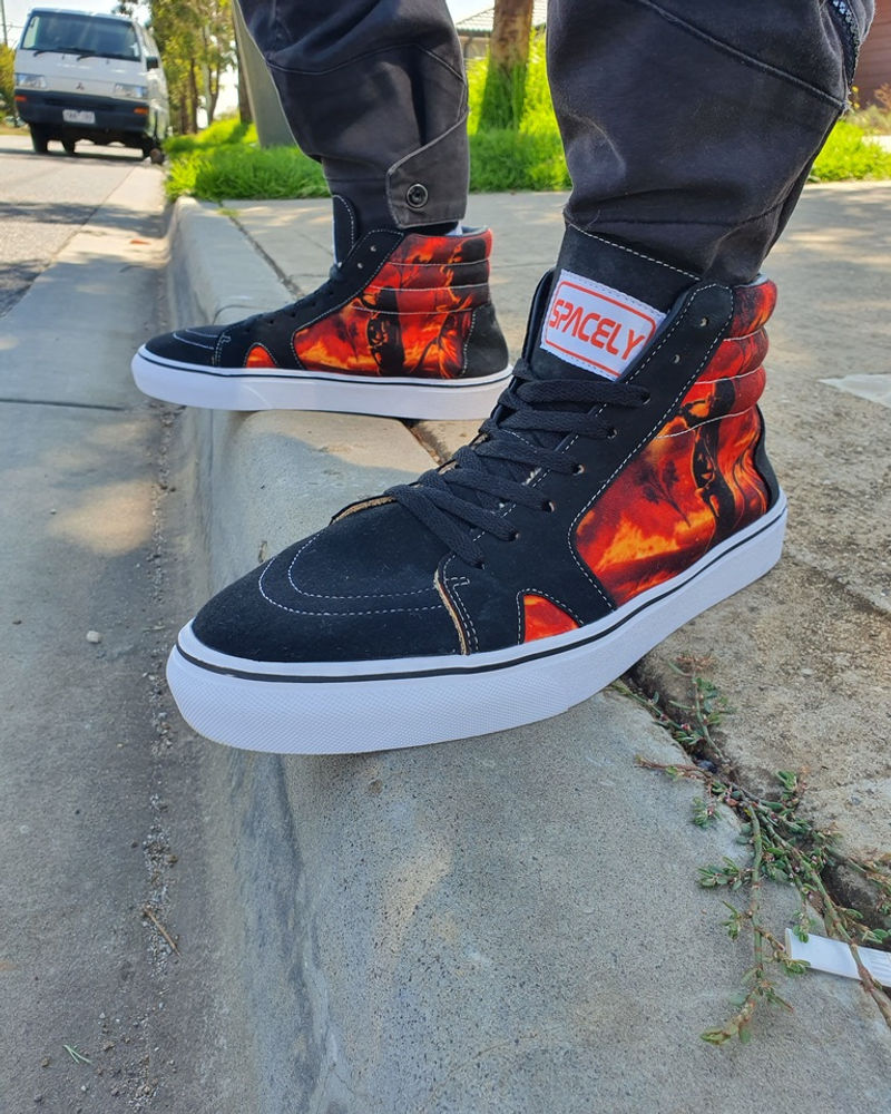 Spacely high-top sneakers with flame print worn on a skate ledge
