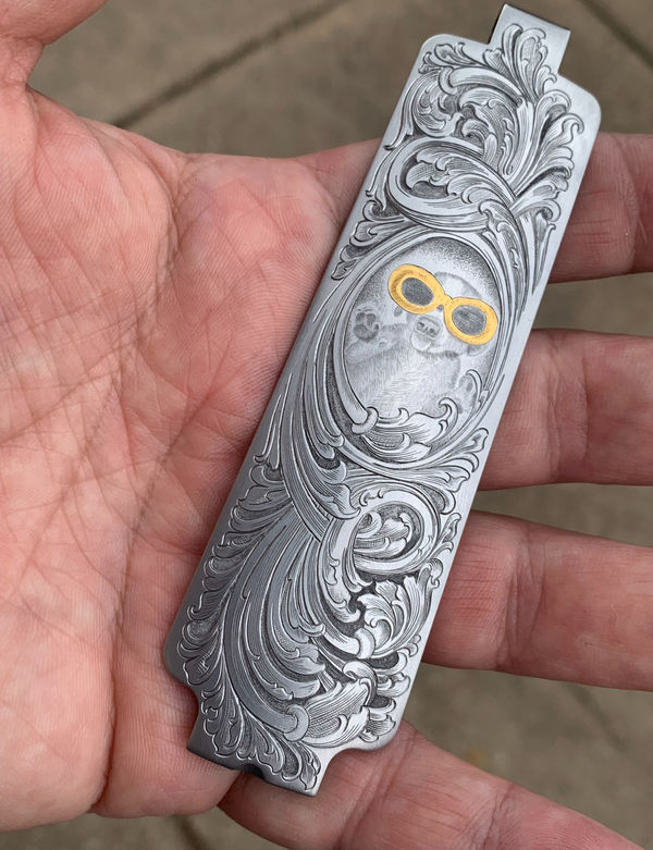 Hand holding an engraved silver panel with gold inlay