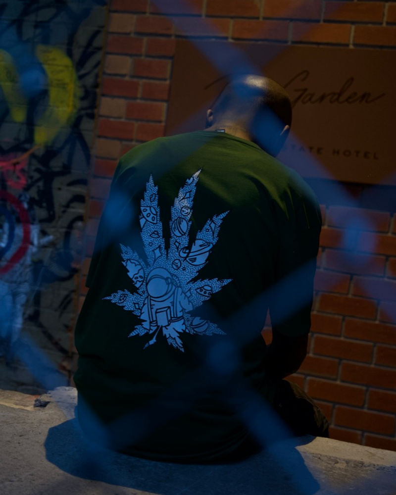 Back of a Spacely leaf-graphic tee against a brick wall