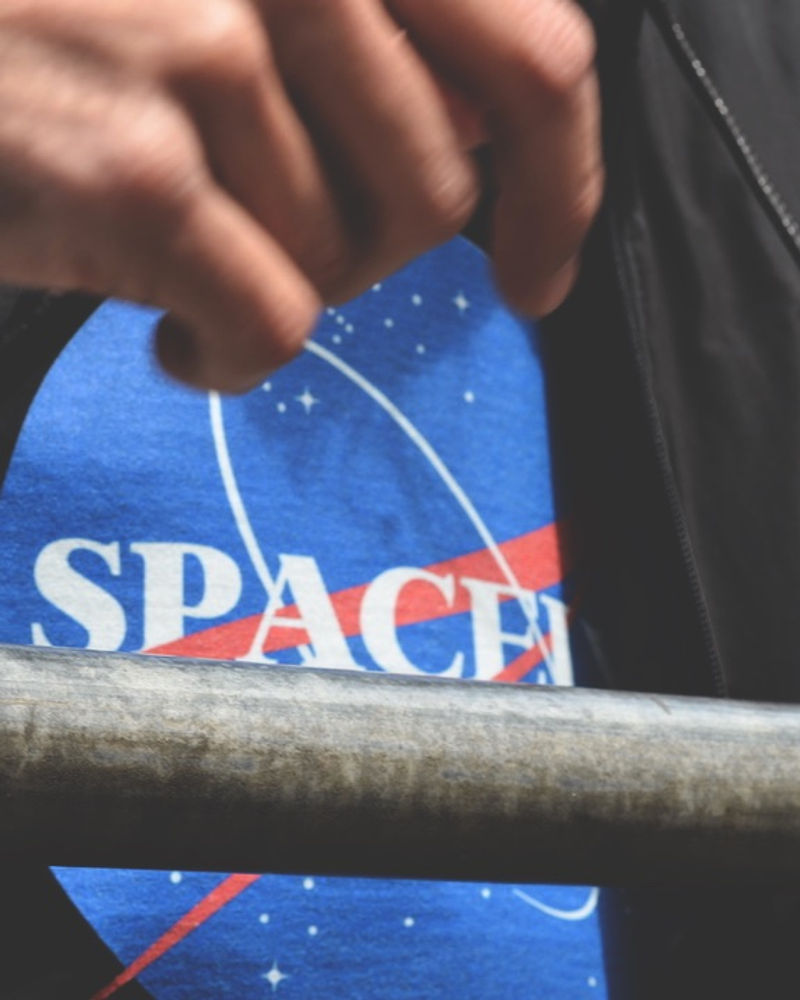 Hand holding a Spacely cap over a railing
