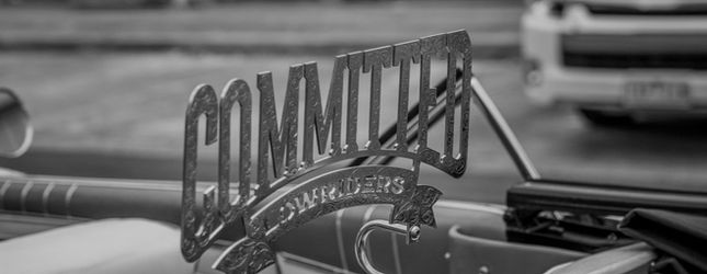Committed Lowriders club plaque mounted on a car, in black and white