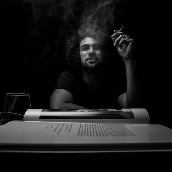 Black and white portrait of a man smoking behind a typewriter