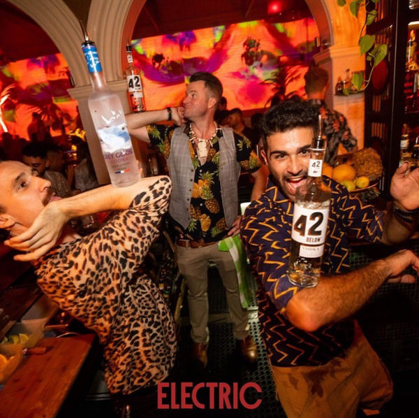 Group posing with bottles behind the bar at Electric