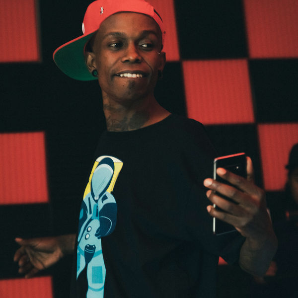 Artist in a Spacely tee against a red and black checkered wall