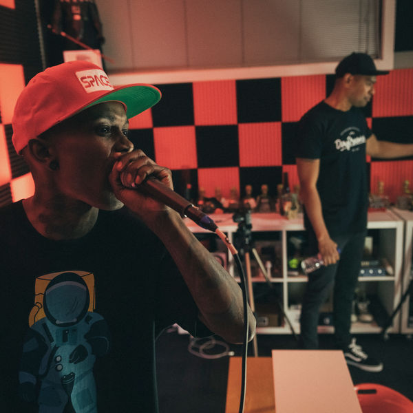 Artist recording vocals while an engineer works behind him