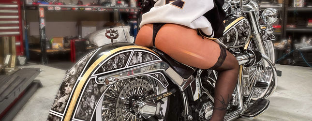 Model posing with a fully engraved gold and chrome lowrider bicycle at a show