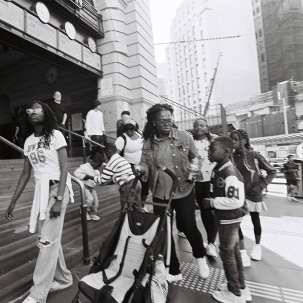 Black and white street photograph by Scott Ransley capturing family group on Flinders Street Station steps, Melbourne documentary photography