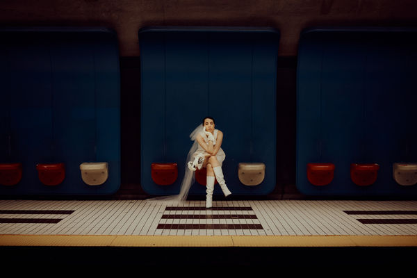 Figure seated on a red bench in a blue-walled interior, shot on film