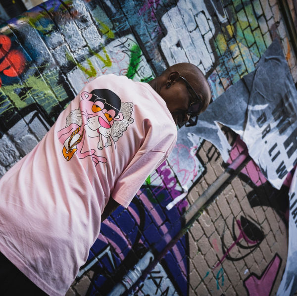 Model in a pink Spacely hoodie against a graffiti laneway wall