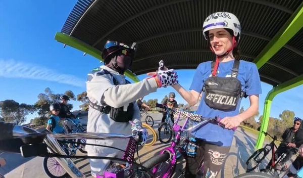 Two riders bumping fists at a bike meet under a shelter