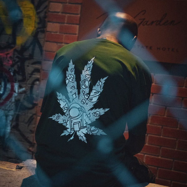 Back of a Spacely tee with a white leaf graphic against a brick wall