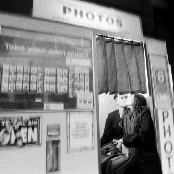 Black and white film photograph by Scott Ransley of woman smoking in photo booth at night, Melbourne street photography