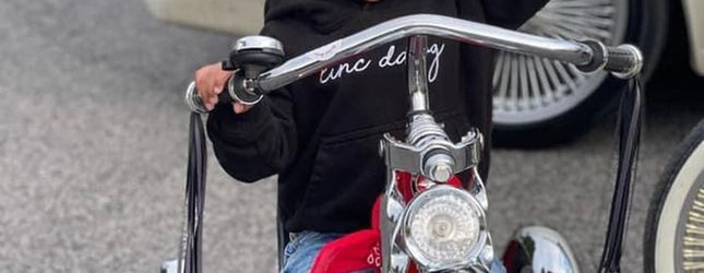 Rider gripping the twisted chrome handlebars of a lowrider bicycle