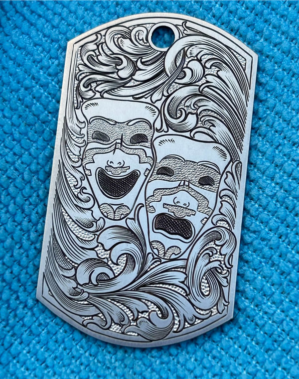 Engraved silver dog tag with theatre masks and scrollwork