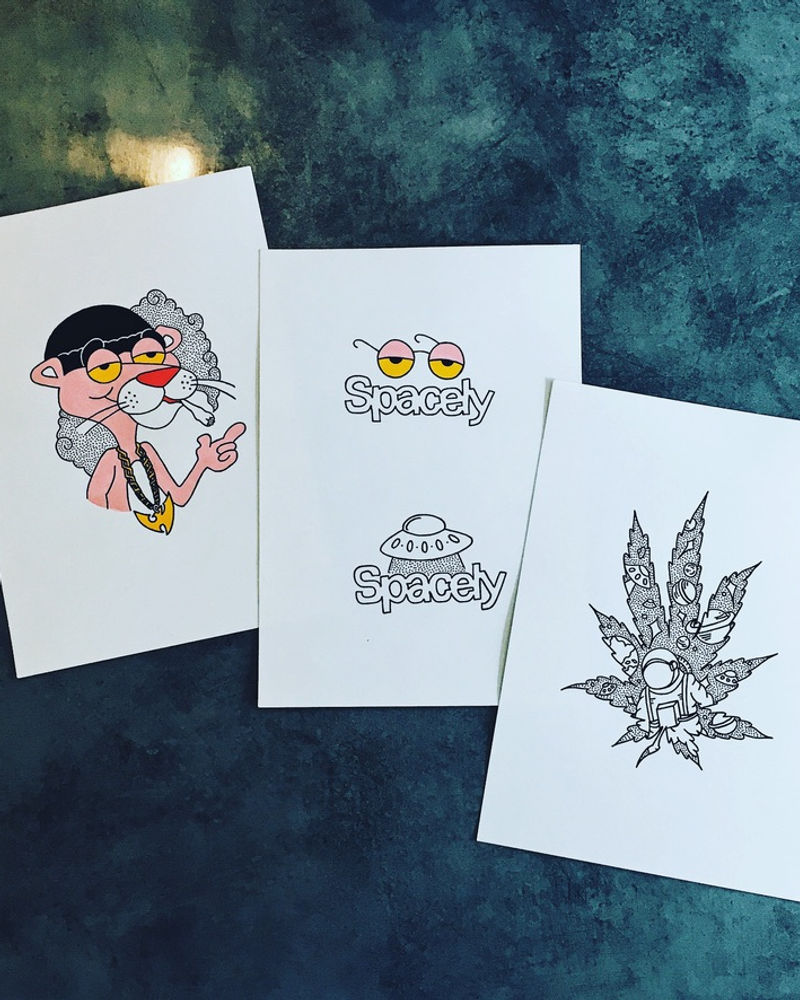 Spacely sticker and print artwork laid out on a desk