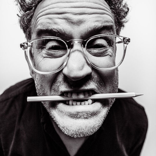 Black and white portrait of a man in glasses biting a pencil