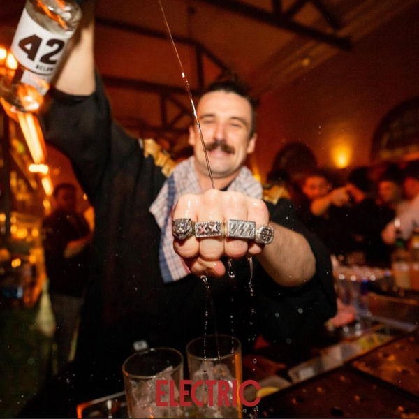 Bartender pouring a drink behind the bar at Electric