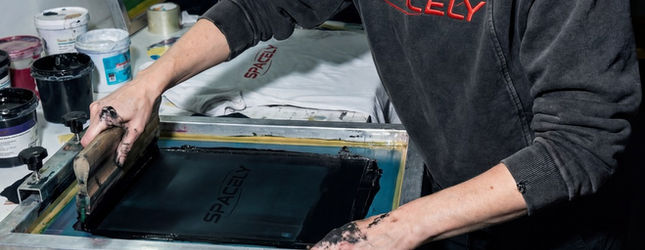 Screen printer pulling a Spacely print through the screen