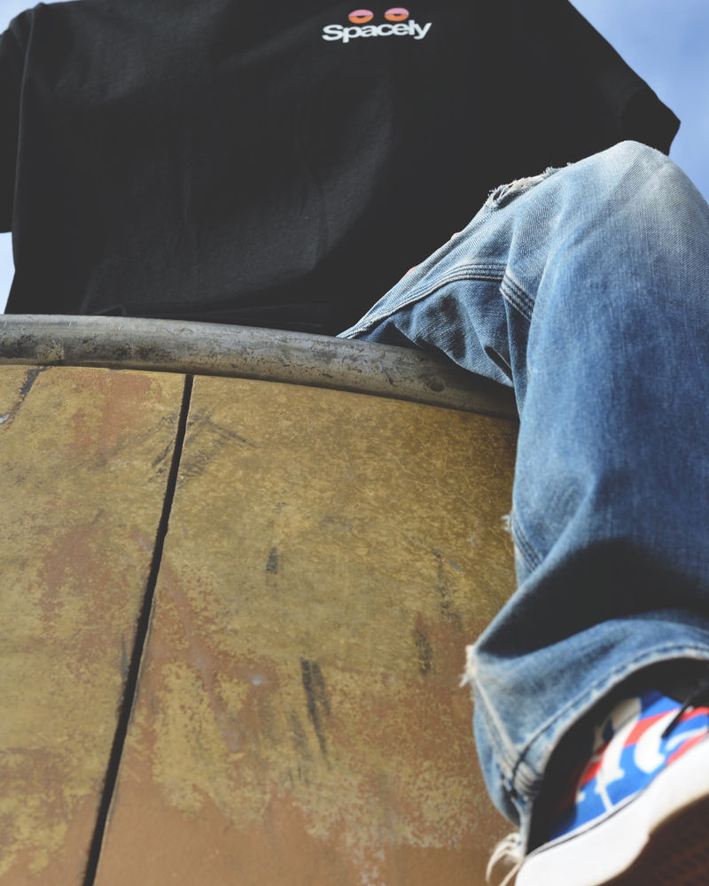 Person in a Spacely windbreaker seated on a concrete ledge