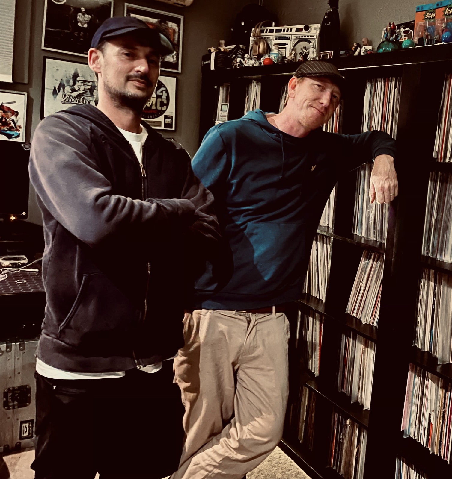 DJ Rellik and DJ Intalink in front of the record wall in the studio