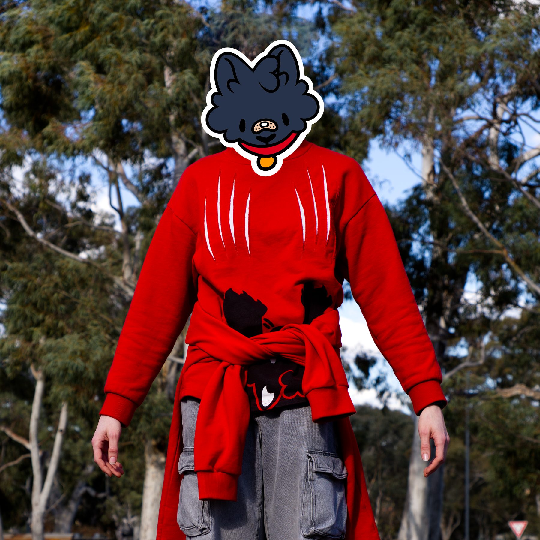 A figure in a slashed red crewneck with the Vandal cat mask, standing in a eucalypt park