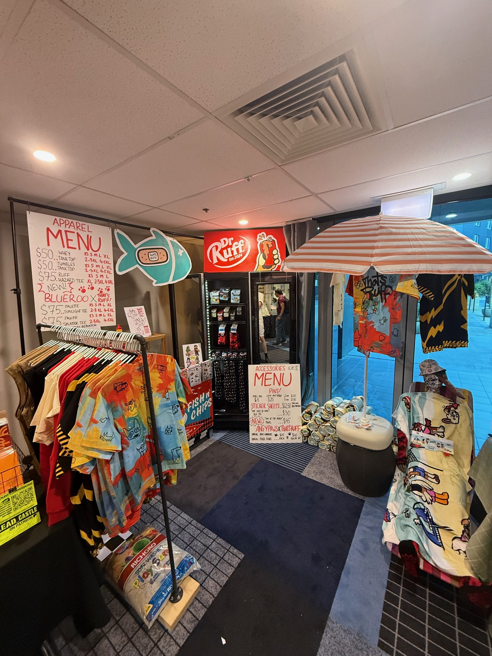 A market setup dressed as a chip shop, hand-drawn menu boards and a striped umbrella